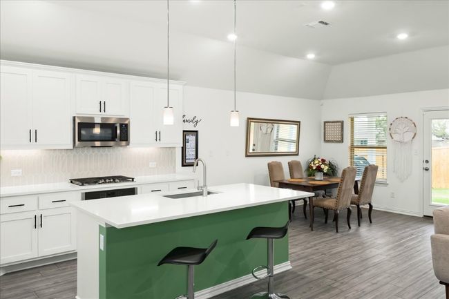 Kitchen featuring a center island with sink, a sink, stainless steel appliances, vaulted ceiling, and backsplash | Image 5