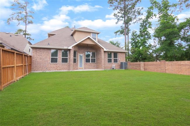 This photo showcases a spacious backyard with a well-maintained lawn, bordered by a wooden and brick fence. The brick house features multiple windows and 2 covered patios, ideal for family gatherings and outdoor activities. | Image 42