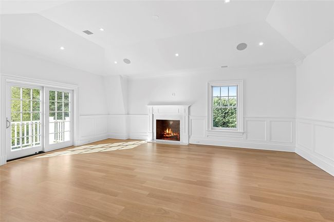 Primary bedroom featuring plenty of natural light, vaulted ceiling, a fireplace with flush hearth, a wainscoted wall, and a decorative wall | Image 22