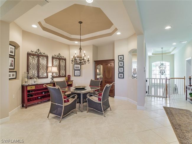 Dining area with a notable chandelier, light tile floors, and a raised ceiling | Image 12