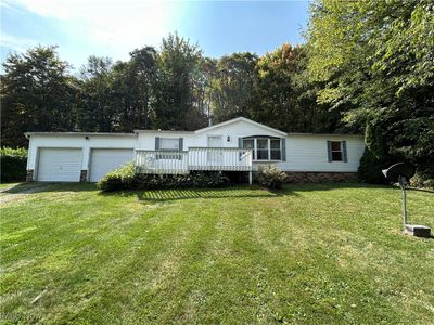 View of front of home with a front yard, a wooden deck, and a garage | Image 1