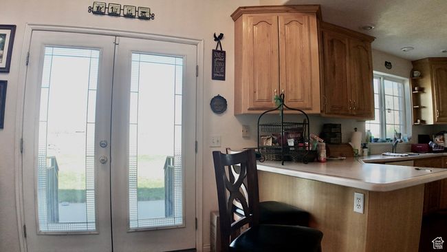 Kitchen featuring a kitchen bar, a peninsula, french doors, and light countertops | Image 50