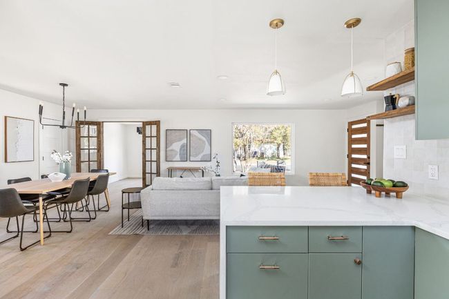 Kitchen featuring green cabinets, a peninsula, light wood-style flooring, a chandelier, and open shelves | Image 18