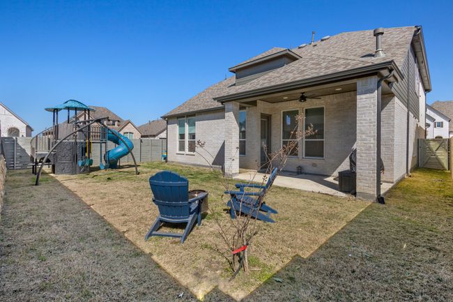 Rear view of property with a patio area, a playground, a fenced backyard, and a shingled roof | Image 29