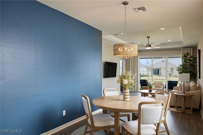 Dining area with dark wood-style floors, a tray ceiling, visible vents, and baseboards | Image 7