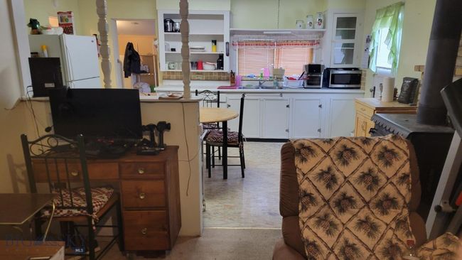Kitchen with white cabinets, white refrigerator, a breakfast bar area, and sink | Image 13