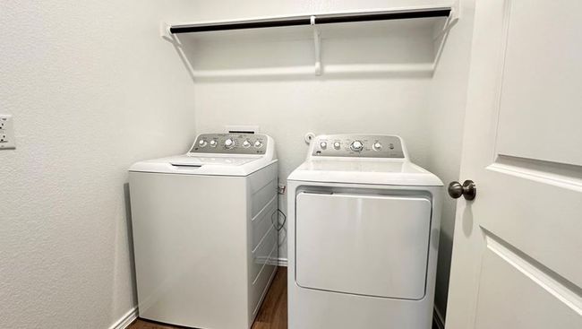 Laundry room with washing machine and clothes dryer, a textured wall, and wood finished floors | Image 5