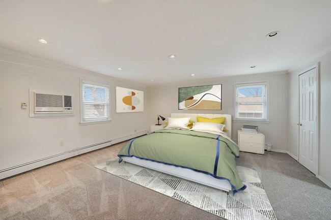 Bedroom featuring light colored carpet, a baseboard radiator, crown molding, and a wall mounted air conditioner | Image 19