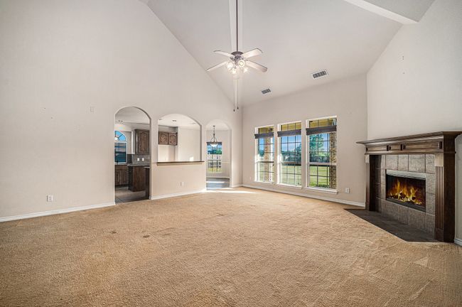 Unfurnished living room featuring high vaulted ceiling, a fireplace, carpet floors, a ceiling fan, and healthy amount of natural light | Image 8