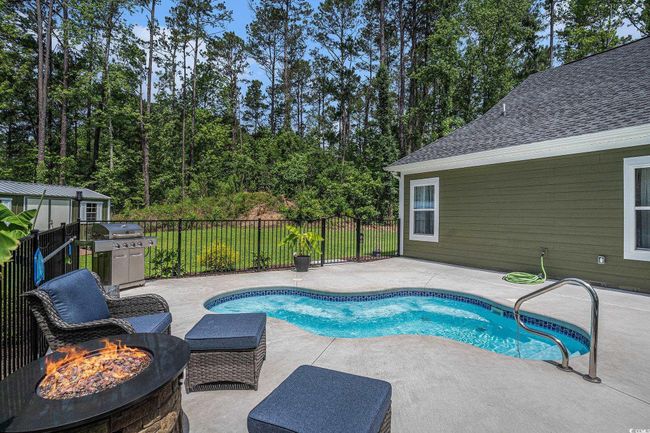 View of swimming pool with a patio area, a fire pit, fence, and grilling area | Image 33