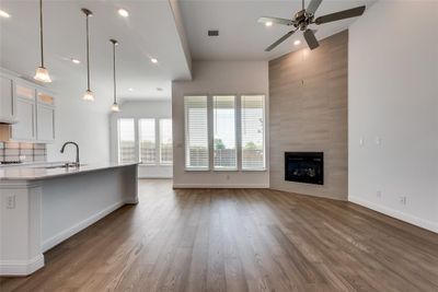 Kitchen with hardwood / wood-style flooring, ceiling fan, a tile fireplace, and white cabinetry | Image 3