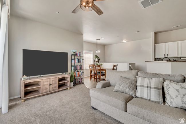 Living area featuring a ceiling fan, visible vents, and light carpet | Image 6