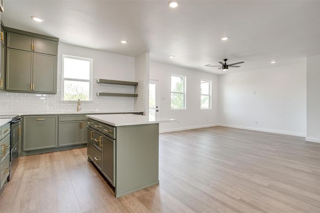 Kitchen featuring ceiling fan, electric range, green cabinets, a sink, and light wood finished floors | Image 13