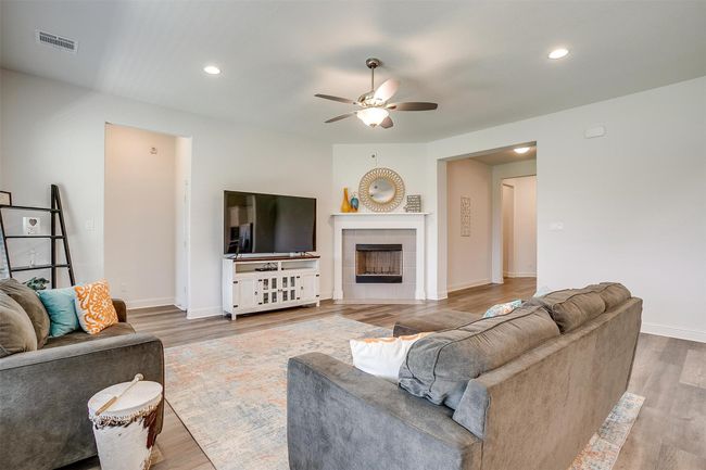 Living room with a ceiling fan, wood finished floors, a tiled fireplace, baseboards, and recessed lighting | Image 9