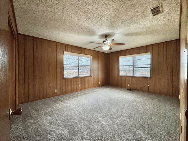 Spare room with ceiling fan, carpet floors, a textured ceiling, and wood walls | Image 20