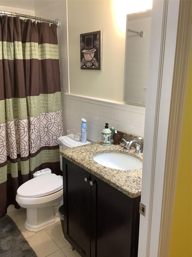 Bathroom with vanity, tile walls, tile patterned floors, wainscoting, and a shower with curtain | Image 4