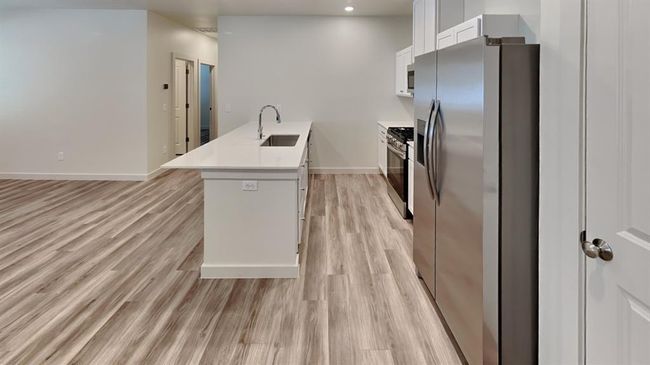Kitchen with a sink, appliances with stainless steel finishes, baseboards, light wood finished floors, and a peninsula | Image 9