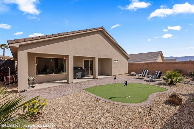 Rear view of property featuring a putting area, a patio area, stucco siding, and fence | Image 57