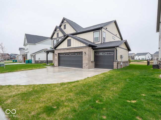 view of front of property with a front yard, brick siding, driveway, and board and batten siding | Image 4