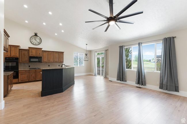 Kitchen featuring black appliances, ceiling fan, light wood finished floors, an island with sink, and recessed lighting | Image 13