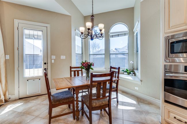 Dining space with light tile patterned flooring, baseboards, and an inviting chandelier | Image 12