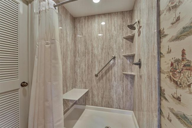 An updated shower features a built-in seat and shelving for convenient storage. | Image 23