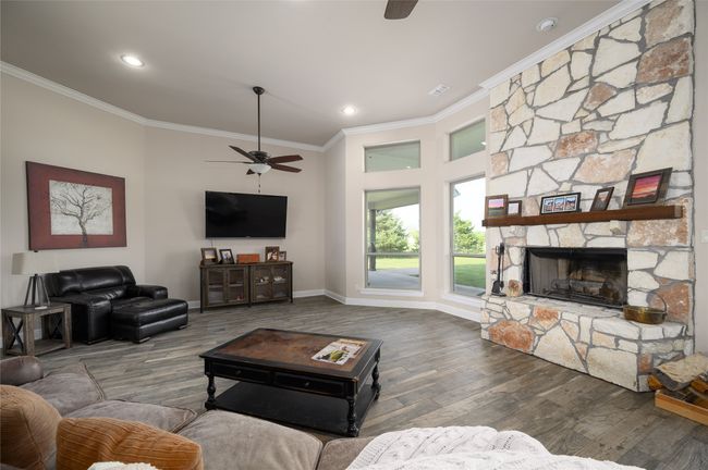 Family room with a ceiling fan, crown molding, wood finished floors, a fireplace, and baseboards | Image 8
