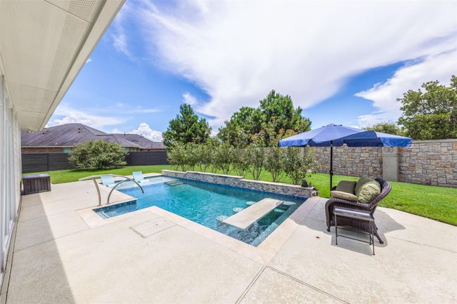 This view of the pool reveals an expansive area of cool decking, providing ample space for seating and relaxation. The generous decking enhances the poolside experience, offering plenty of room for lounging and enjoying the outdoor environment. | Image 35