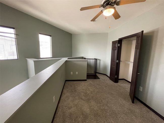 Hallway with an upstairs landing, carpet, and baseboards | Image 23