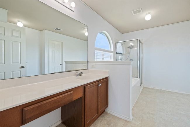 Full bath featuring a shower with shower door, vanity, a tub to relax in, baseboards, and tile patterned floors | Image 24
