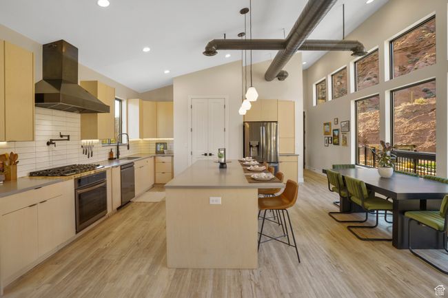 Kitchen featuring stainless steel appliances, ventilation hood, modern cabinets, a breakfast bar, and a sink | Image 10