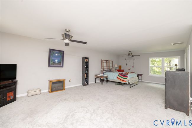 Bedroom with carpet floors, a ceiling fan, and a glass covered fireplace | Image 40