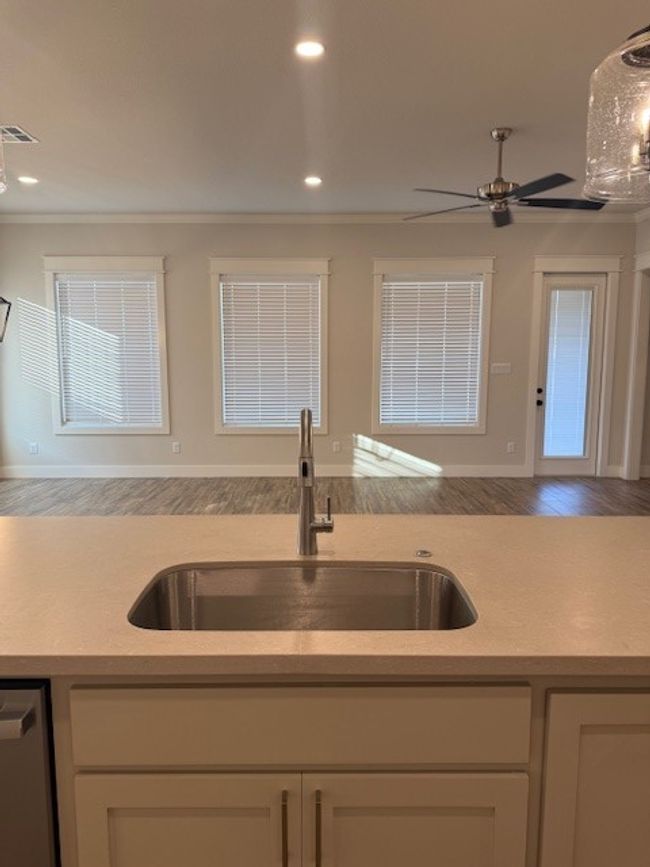 Kitchen featuring ceiling fan, ornamental molding, light countertops, wood finished floors, and dishwasher | Image 12