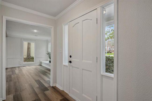 The charismatic entry provides natural light coming through the windows, and leads into the family-room on the right side with wood-style flooring and large windows, creating a welcoming atmosphere. | Image 5