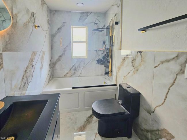 Bathroom with tile walls, shower / bathing tub combination, vanity, and toilet | Image 31