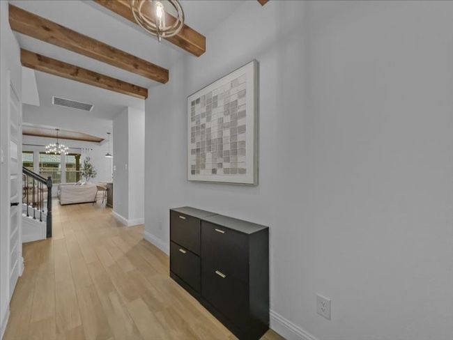Corridor with a chandelier, beam ceiling, baseboards, light wood-type flooring, and stairway | Image 4