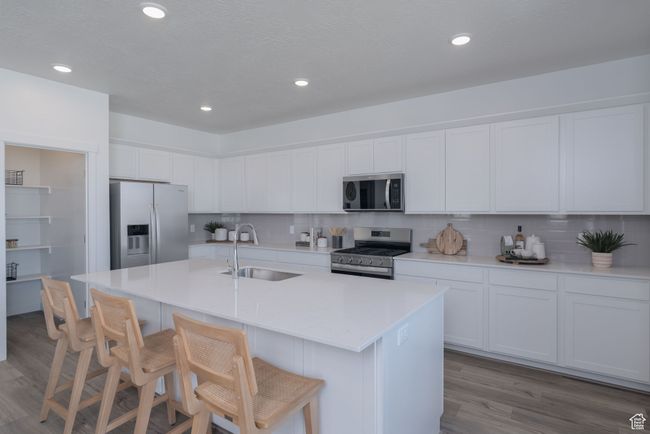 Kitchen with appliances with stainless steel finishes, light wood-style floors, decorative backsplash, white cabinetry, and recessed lighting | Image 19