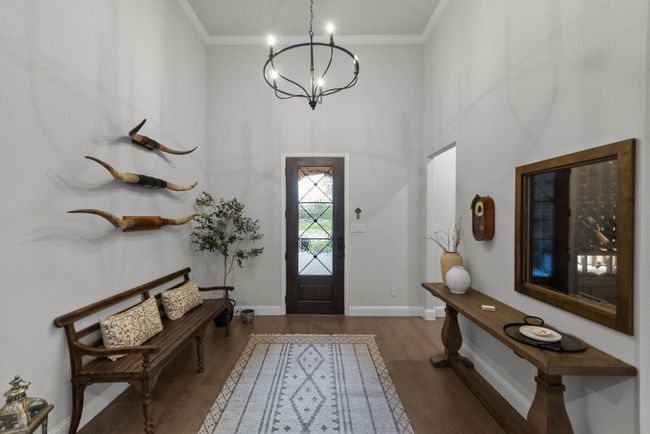 Welcoming foyer highlighted by an elegant chandelier, wood floors, and tall ceiling | Image 6