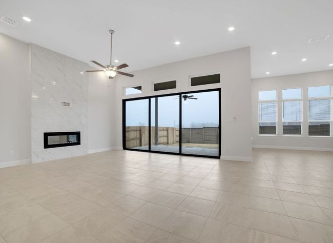 Unfurnished living room featuring visible vents, light tile patterned floors, a ceiling fan, recessed lighting, and a premium fireplace | Image 6