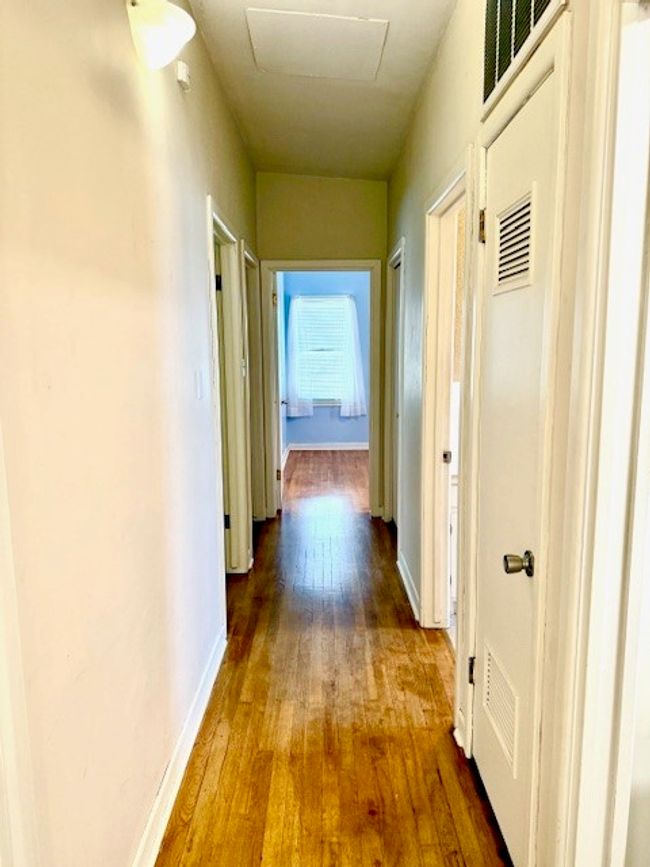Hall with baseboards, visible vents, attic access, and hardwood / wood-style flooring | Image 19