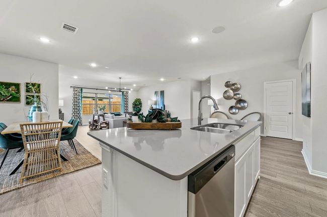 Kitchen featuring stainless steel dishwasher, a sink, recessed lighting, light wood-style flooring, and white cabinetry | Image 17