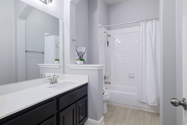 Bathroom featuring shower / bath combo with shower curtain, toilet, wood finished floors, and vanity | Image 25