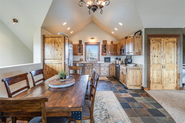 Caretaker Quarters / Guest House. Dining room with a notable chandelier, stone finish floor, recessed lighting, baseboards, and vaulted ceiling | Image 71