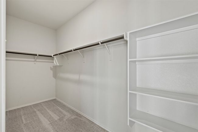 Spacious primary closet featuring carpet flooring, built in shelves | Image 22