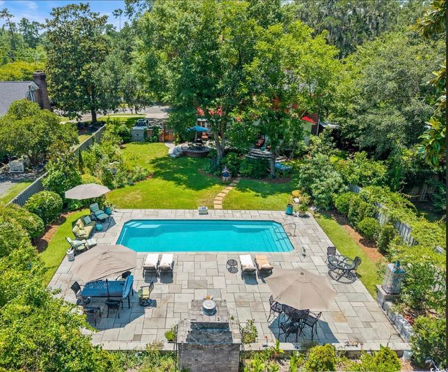 Outdoor pool with a patio and view of scattered trees | Image 5