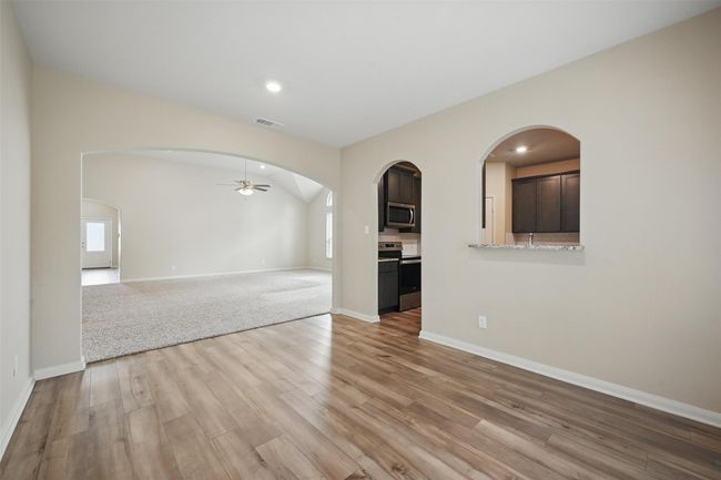 Unfurnished living room featuring light wood-type flooring, baseboards, visible vents, ceiling fan, and arched walkways | Image 9