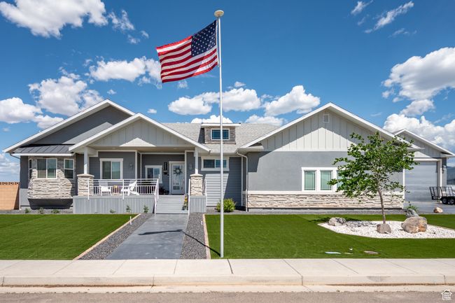 Craftsman-style house featuring stone siding, covered porch, a front lawn, and board and batten siding | Image 6