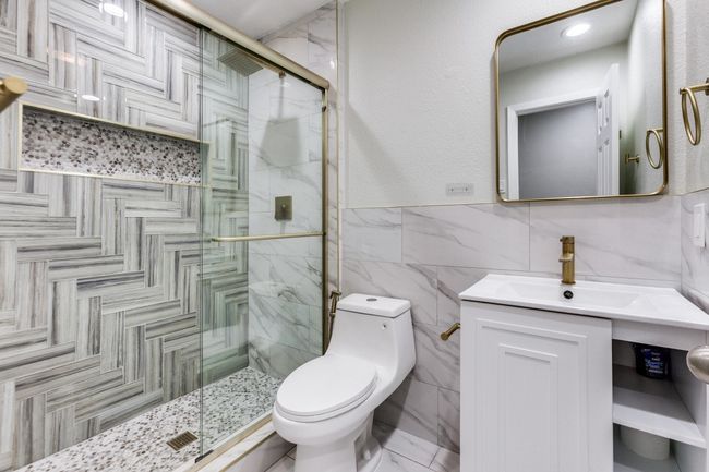 Bathroom featuring a shower stall, tile walls, vanity, and wainscoting | Image 13
