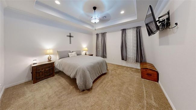 Carpeted bedroom with recessed lighting, a tray ceiling, visible vents, crown molding, and baseboards | Image 30