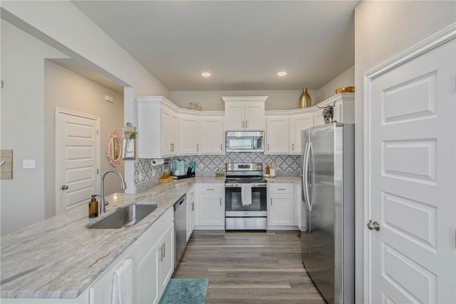 Kitchen featuring appliances with stainless steel finishes, a peninsula, tasteful backsplash, white cabinets, and recessed lighting | Image 11